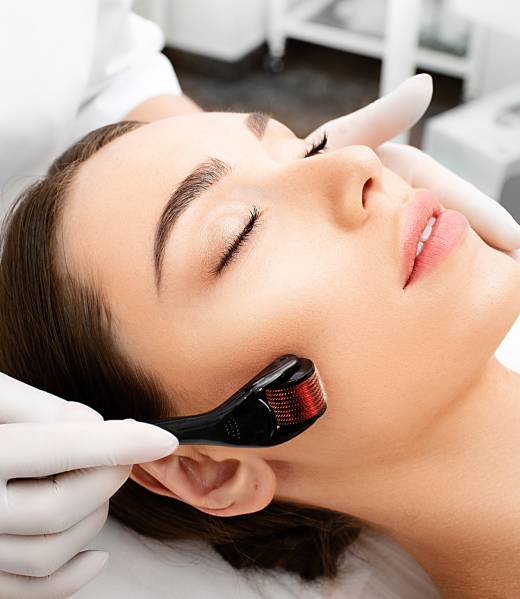 Beautician doing skin treatment using a microneedle derma roller. Woman getting procedure skincare, with mezzo skin roller