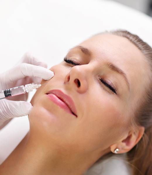 Hands of cosmetologist making botox injection in female lips